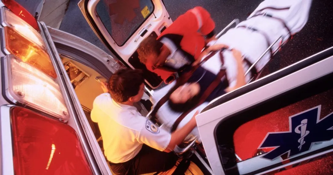 Two EMTs take a patient in a stretcher into an ambulance