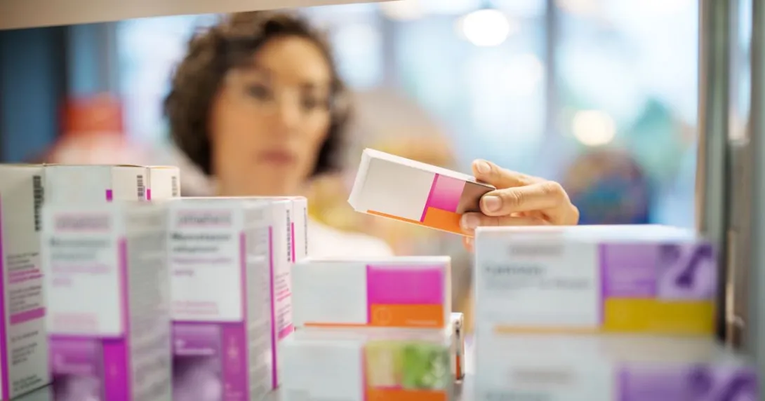 A pharmacist checking a box of medicine in a rack