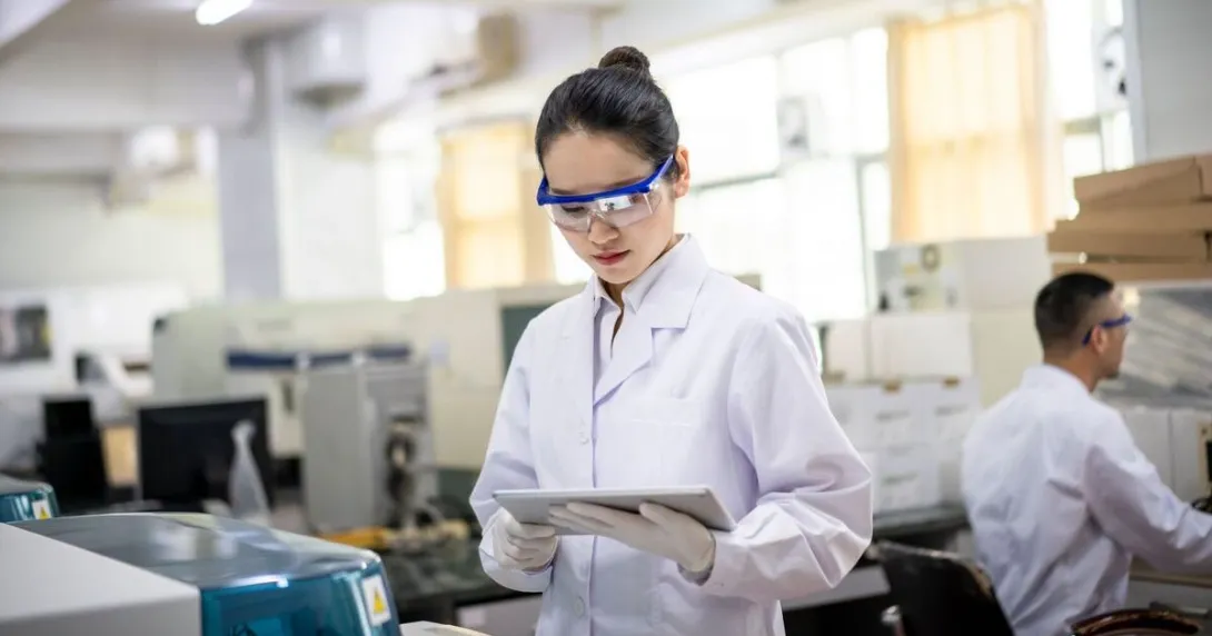 Female clinical researcher in a lab looks at a tablet