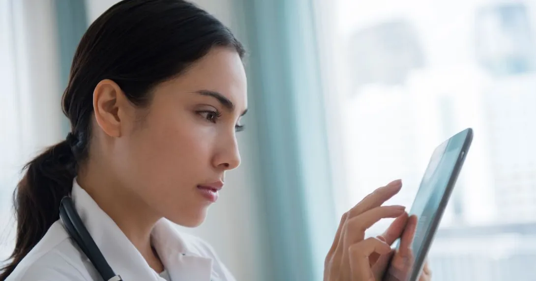 A doctor using a digital tablet to review a patient's file