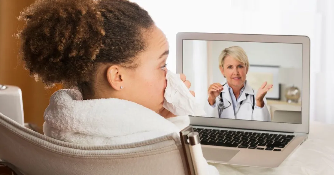 A sick patient consulting with a doctor via video call on a laptop