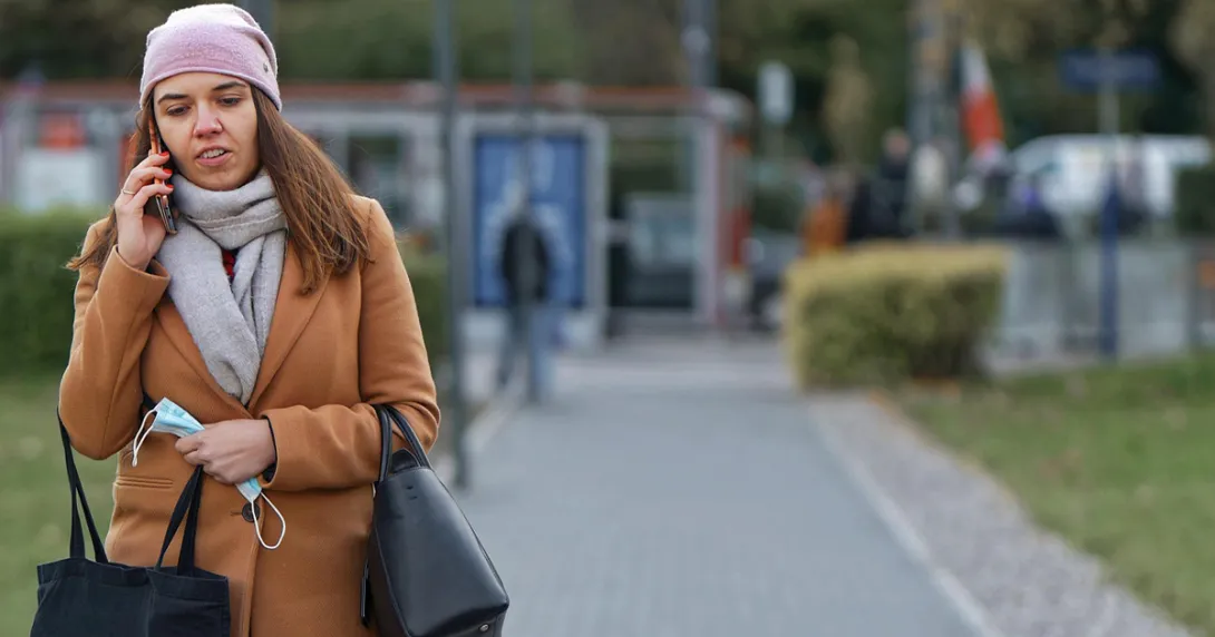 Woman on phone holding mask