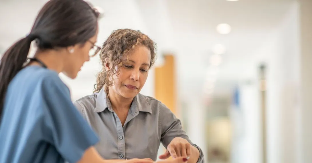 Woman in gray shirt reviews information with a clinician at the hospital
