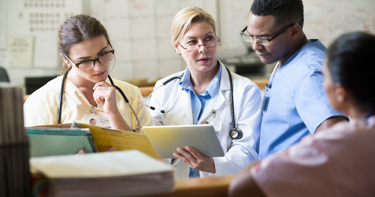 Doctors and nurses discussing a patient's chart from a digital tablet