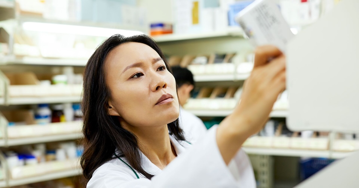 A pharmacist arranging a medicine rack at a pharmacy