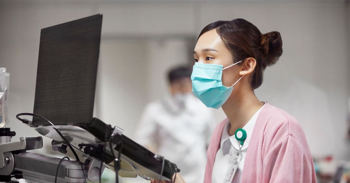 A nurse encoding a patient's record on a laptop